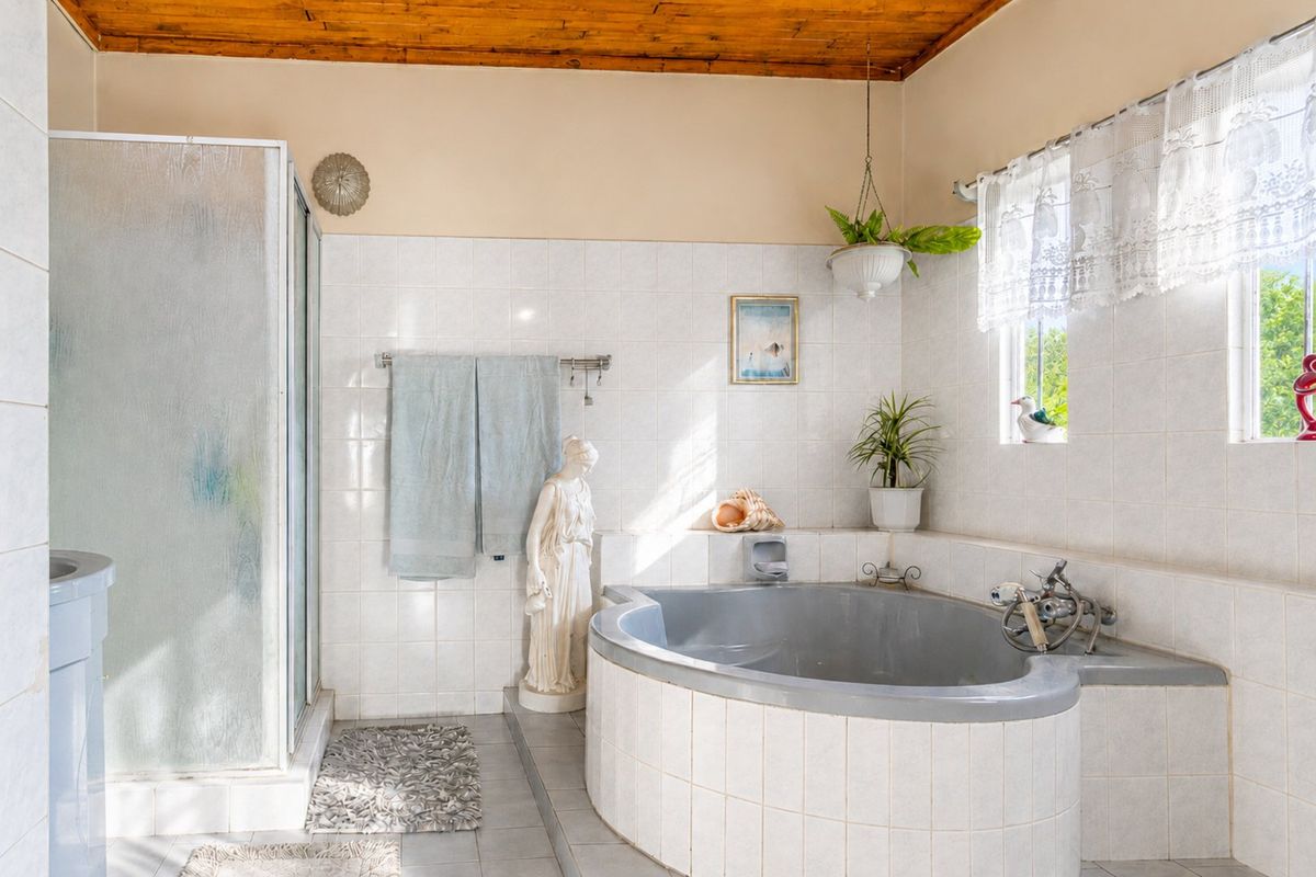 A functional bathroom featuring a built-in corner bathtub, a separate shower enclosure, and classic tiled finishes with a warm timber ceiling.