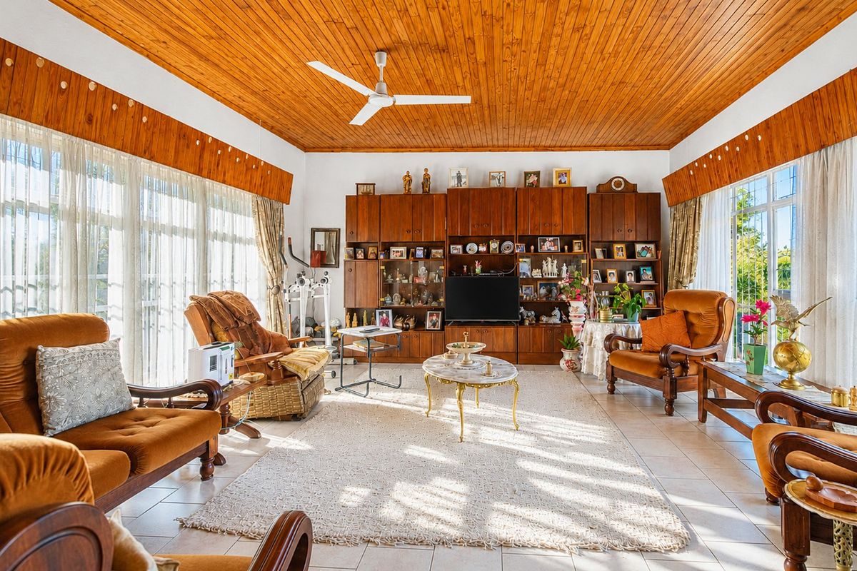 Spacious living room featuring a warm timber-clad ceiling, ceiling fan, tiled flooring, and extensive built-in cabinetry for storage and display.