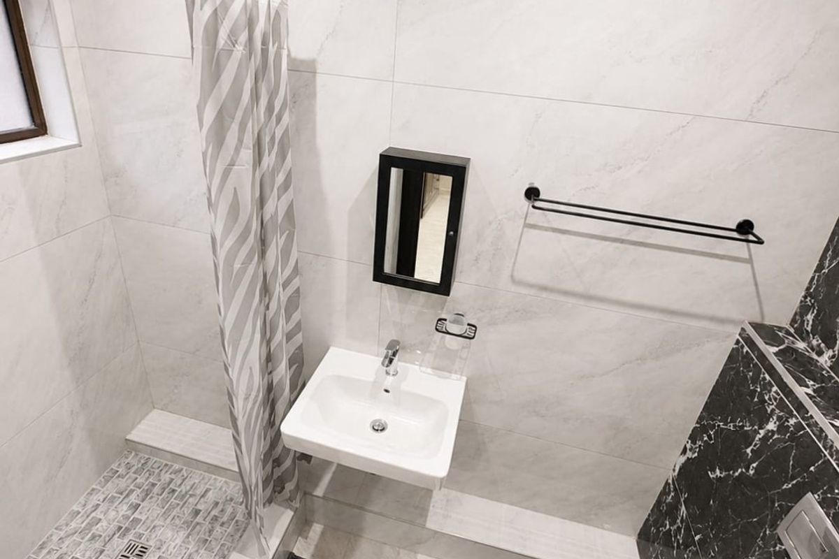 Modern bathroom featuring a wall-mounted basin, wall-hung toilet, and a tiled shower enclosure with contemporary marble-effect wall tiling.