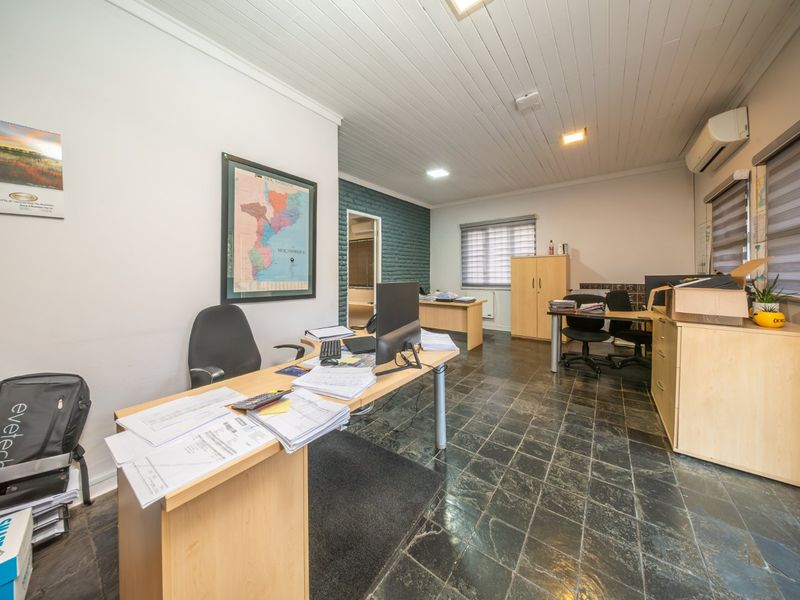 Spacious office area featuring slate tile flooring, an exposed brick feature wall, and a timber-look ceiling with integrated air conditioning.