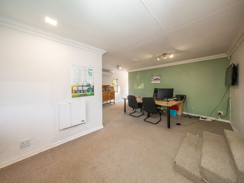 A functional office space featuring carpeted flooring, a raised platform area, split-system air conditioning, and a wall-mounted electric heater.
