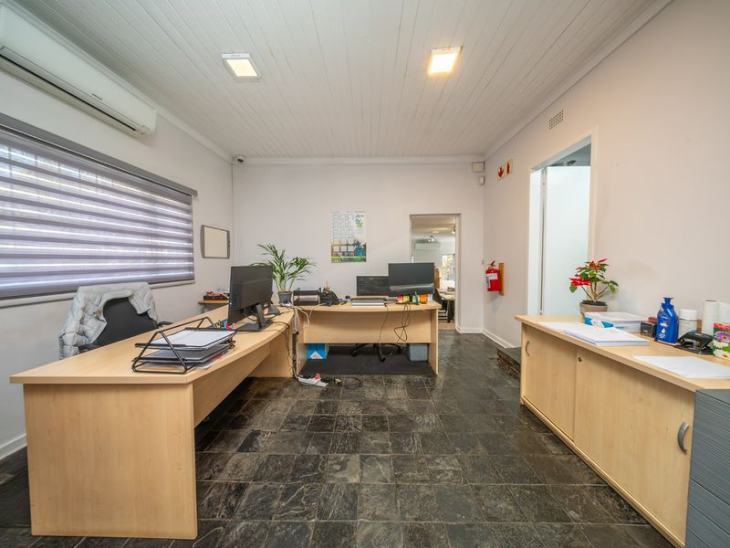 A functional office space featuring stone tile flooring, a tongue and groove ceiling, and a wall-mounted split-system air conditioner.