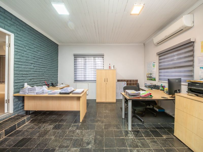Functional office space featuring slate tile flooring, a painted brick feature wall, timber-look panelled ceiling, and a wall-mounted split-system air conditioner.