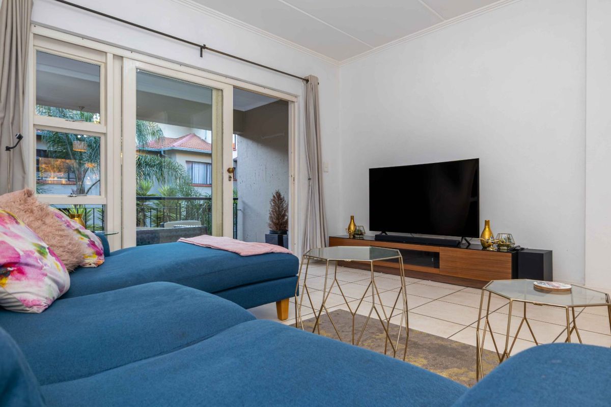 A bright living room featuring tiled flooring and large sliding glass doors that provide access to an outdoor patio area.