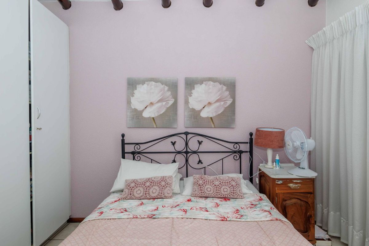 A bedroom featuring exposed timber ceiling beams and a built-in wardrobe, offering a cozy and traditional aesthetic.