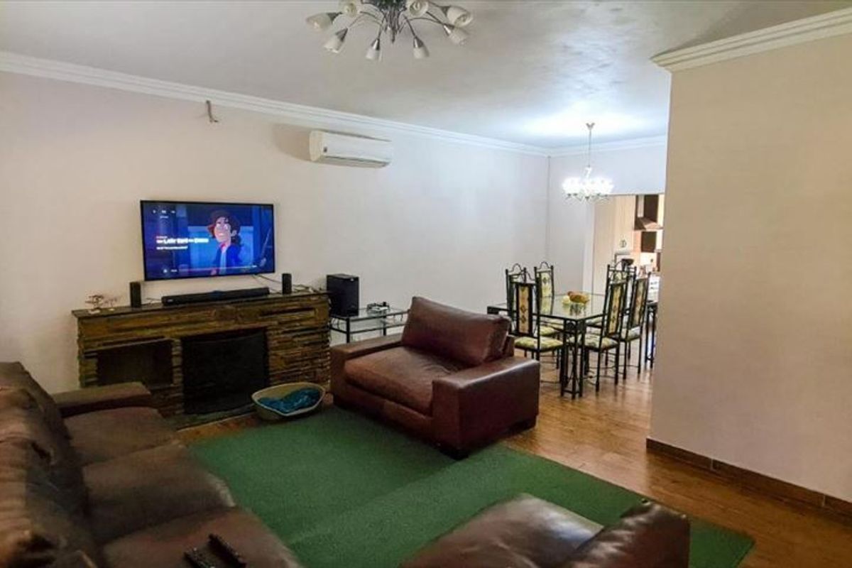 Open-plan living and dining area featuring a stone-clad fireplace, split-system air conditioning, and laminate flooring, providing a functional and connected living space.