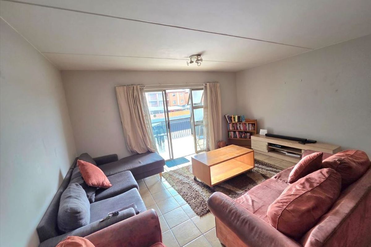 A living room featuring tiled flooring and a sliding glass door providing access to an outdoor area.