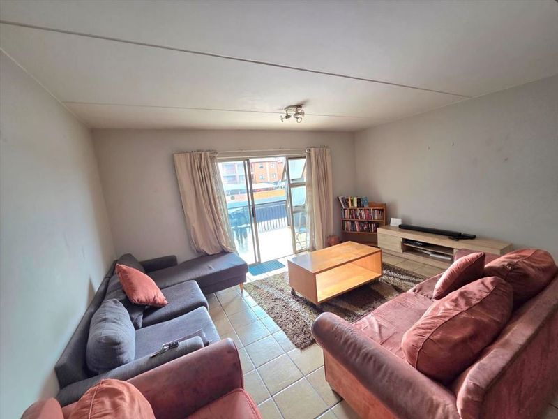 A living room featuring tiled flooring and a sliding glass door providing access to an outdoor area.