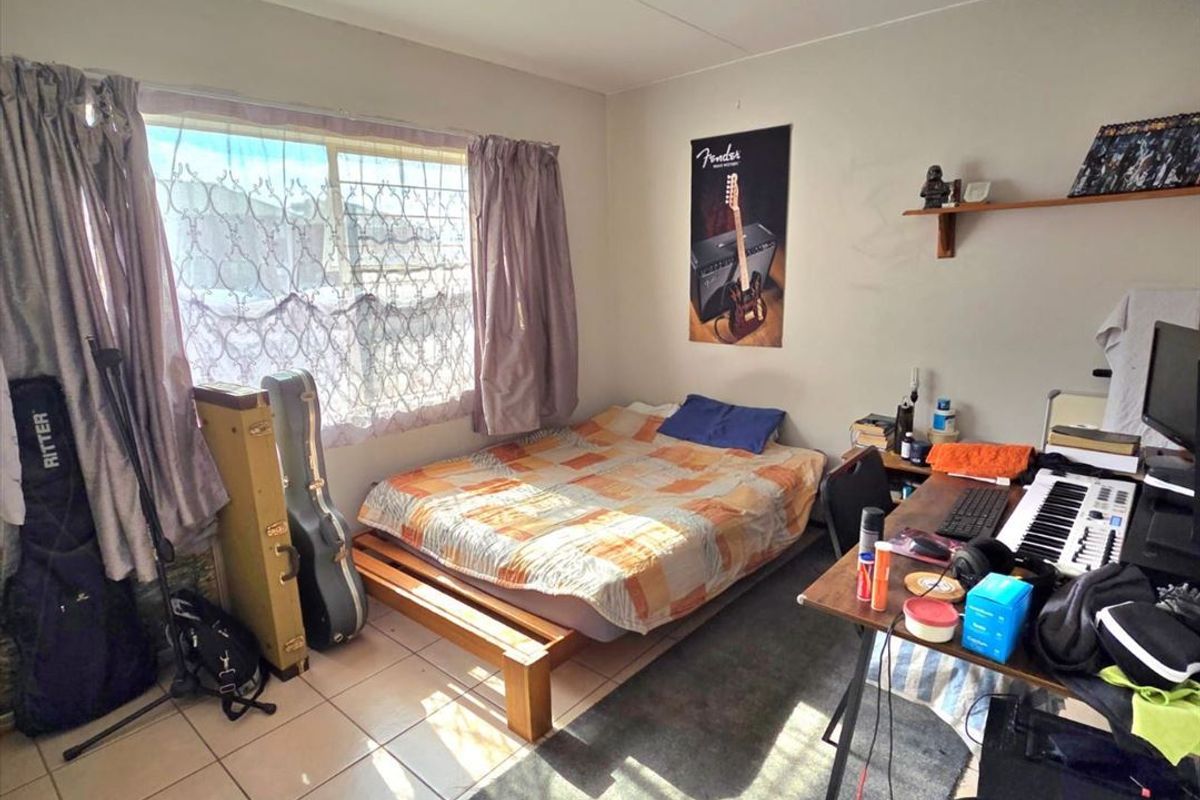 A bedroom featuring tiled flooring and a large window, providing natural light. The space requires cosmetic updates to improve its overall condition.