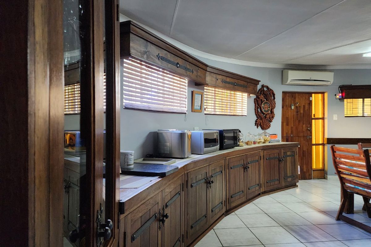 A rustic kitchen area featuring custom wooden cabinetry, tiled flooring, and integrated air conditioning, offering a warm and traditional farm-style aesthetic.