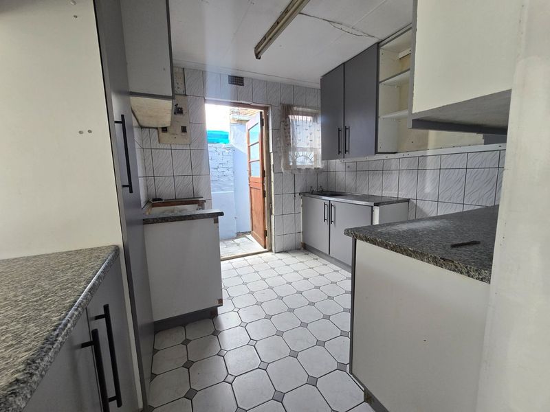 A dated kitchen featuring built-in cabinetry, laminate countertops, and tiled finishes, requiring renovation to modernize the space.
