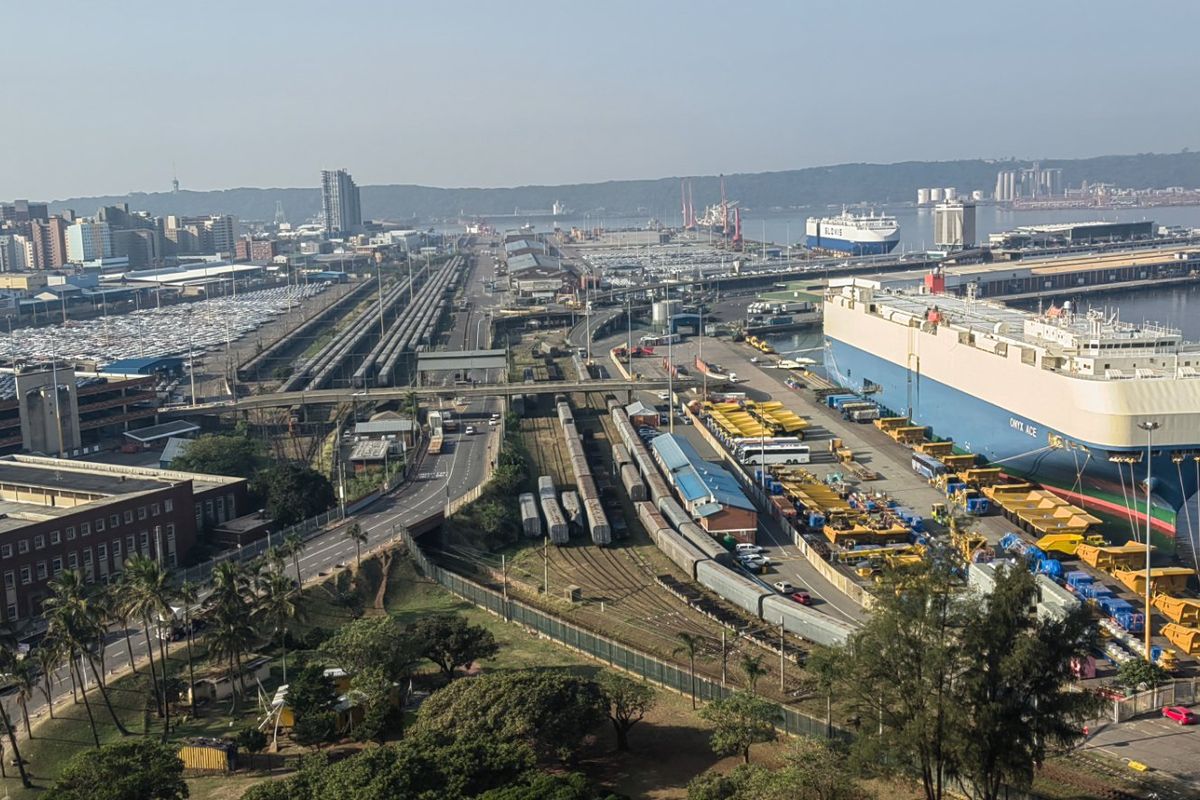 An elevated aerial view overlooking the industrial harbour, shipping port, and surrounding city skyline.