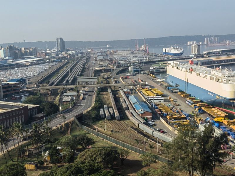 An elevated aerial view overlooking the industrial harbour, shipping port, and surrounding city skyline.