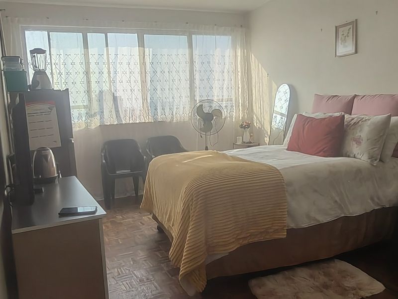 A bedroom featuring parquet flooring and a large window that allows for natural light.