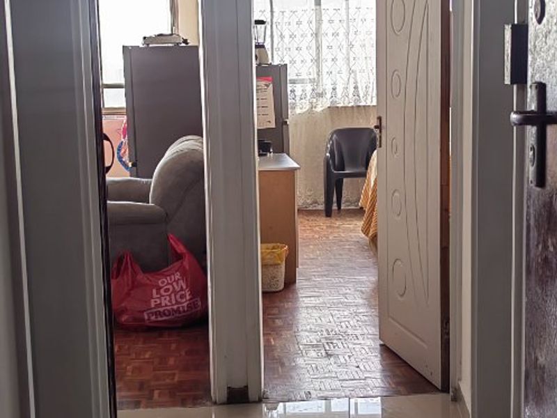 A view from the tiled hallway looking into two adjacent rooms featuring parquet flooring and internal door access.