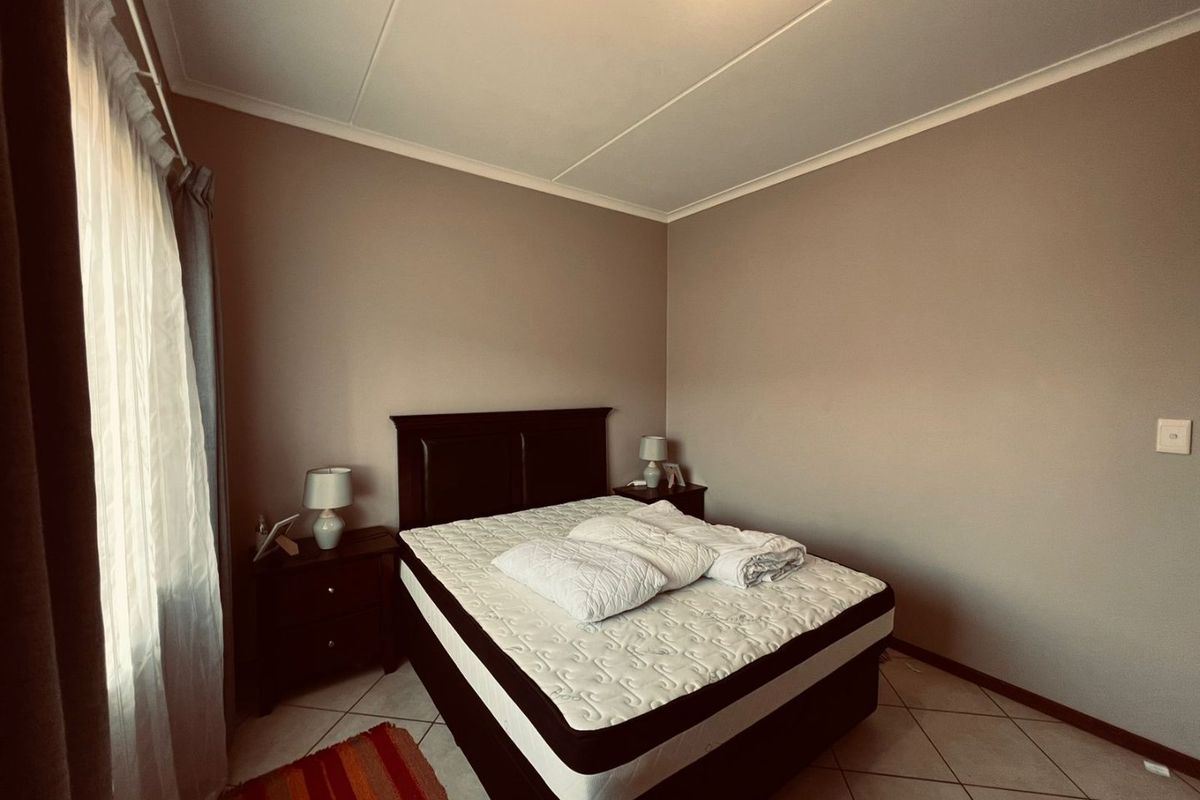 A functional bedroom featuring tiled flooring and neutral wall tones, providing a clean and simple space for rest.