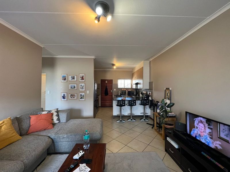 Open-plan living area featuring a kitchen with island, tiled flooring, and neutral wall tones, creating a functional and connected living space.