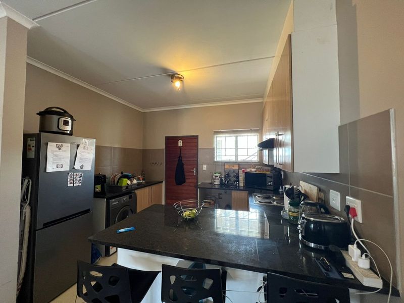 Functional kitchen featuring granite countertops, ample built-in cabinetry, a tiled backsplash, and a breakfast bar area.