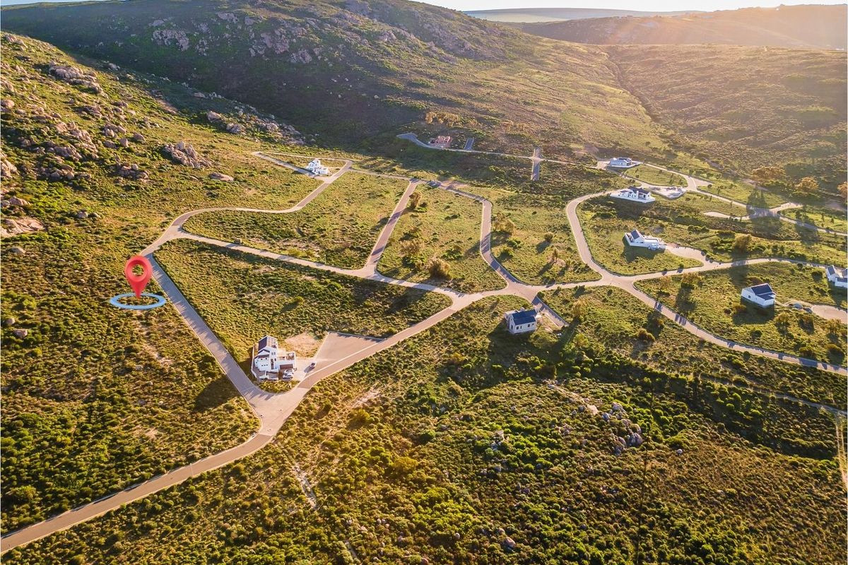Aerial view of a residential estate development featuring vacant plots, paved access roads, and surrounding natural landscape.