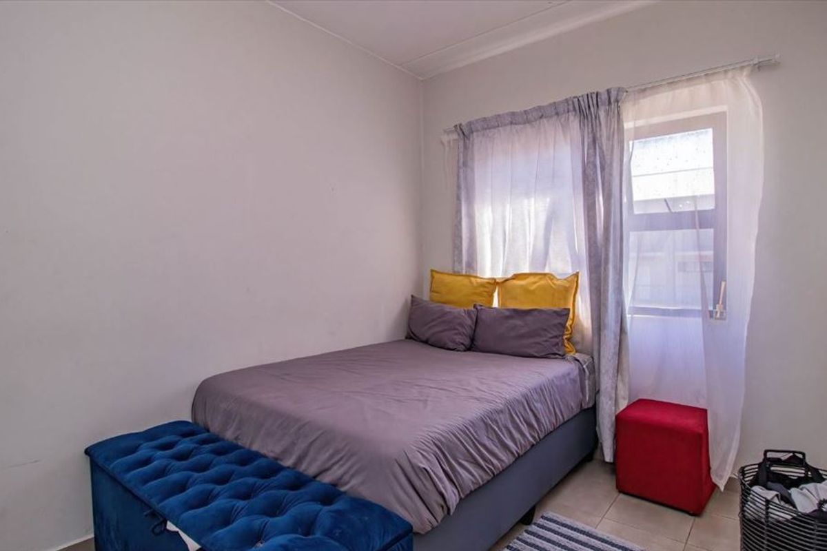A functional bedroom featuring tiled flooring and a window with installed curtain rods, providing a neutral space ready for personalization.