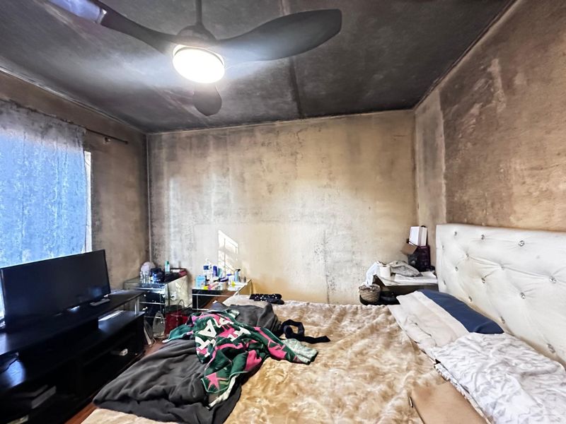A bedroom featuring a ceiling fan, currently requiring significant wall and ceiling restoration due to extensive surface staining and finish damage.