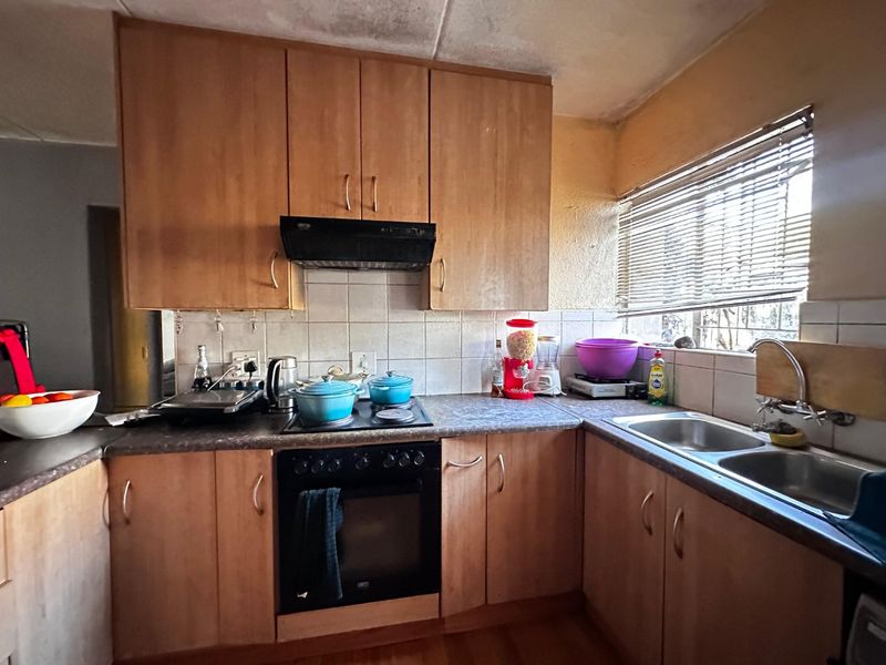 A functional kitchen featuring laminate cabinetry, built-in oven, electric hob, and double bowl sink, requiring cosmetic updates to the walls and ceiling.