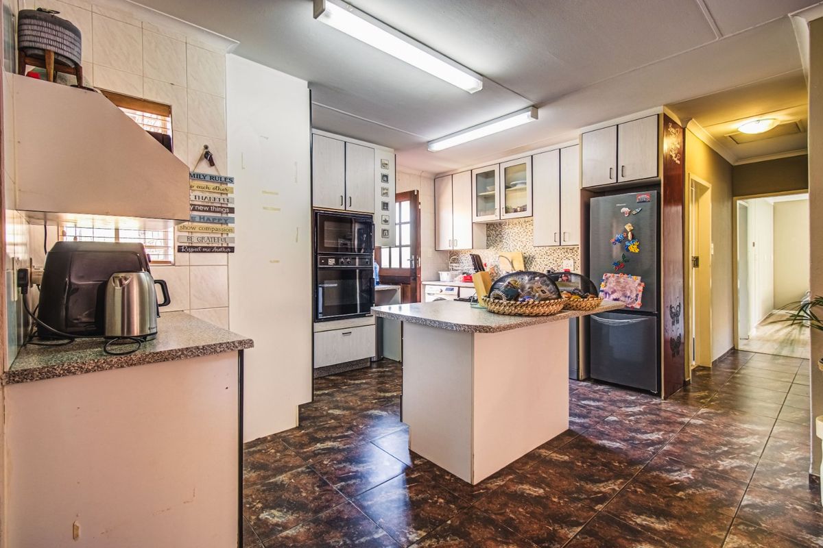 A functional kitchen featuring built-in cabinetry, a central island, integrated oven, and tiled flooring, offering a practical layout for daily meal preparation.