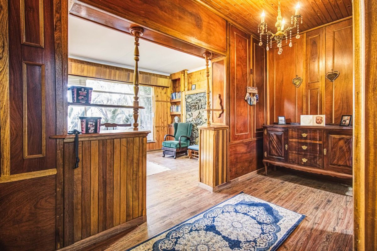 A living area featuring extensive wood paneling, a stone fireplace feature, and a pass-through opening connecting to an adjacent room.