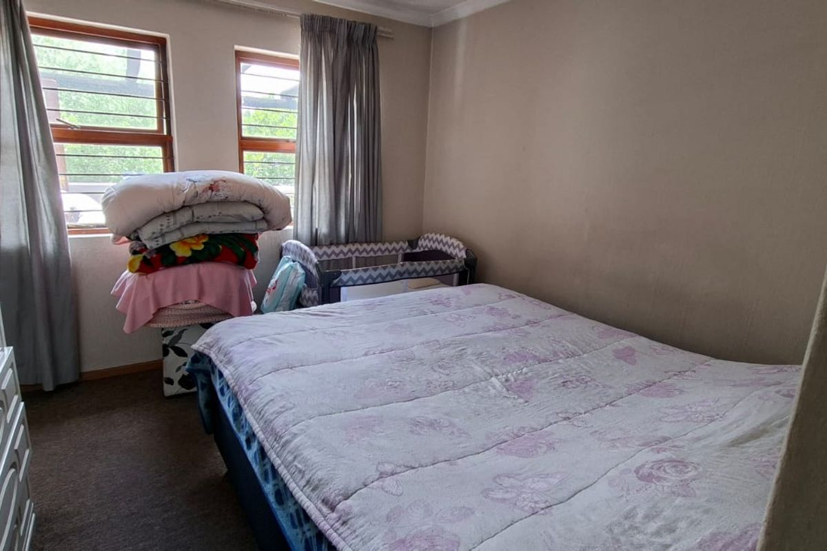 A functional bedroom featuring carpeted flooring and dual windows with security bars, providing natural light and a practical layout.