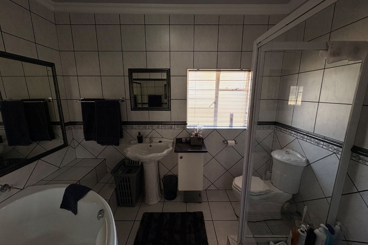 A functional bathroom featuring a pedestal basin, a separate shower enclosure, and a bathtub with tiled wall finishes.