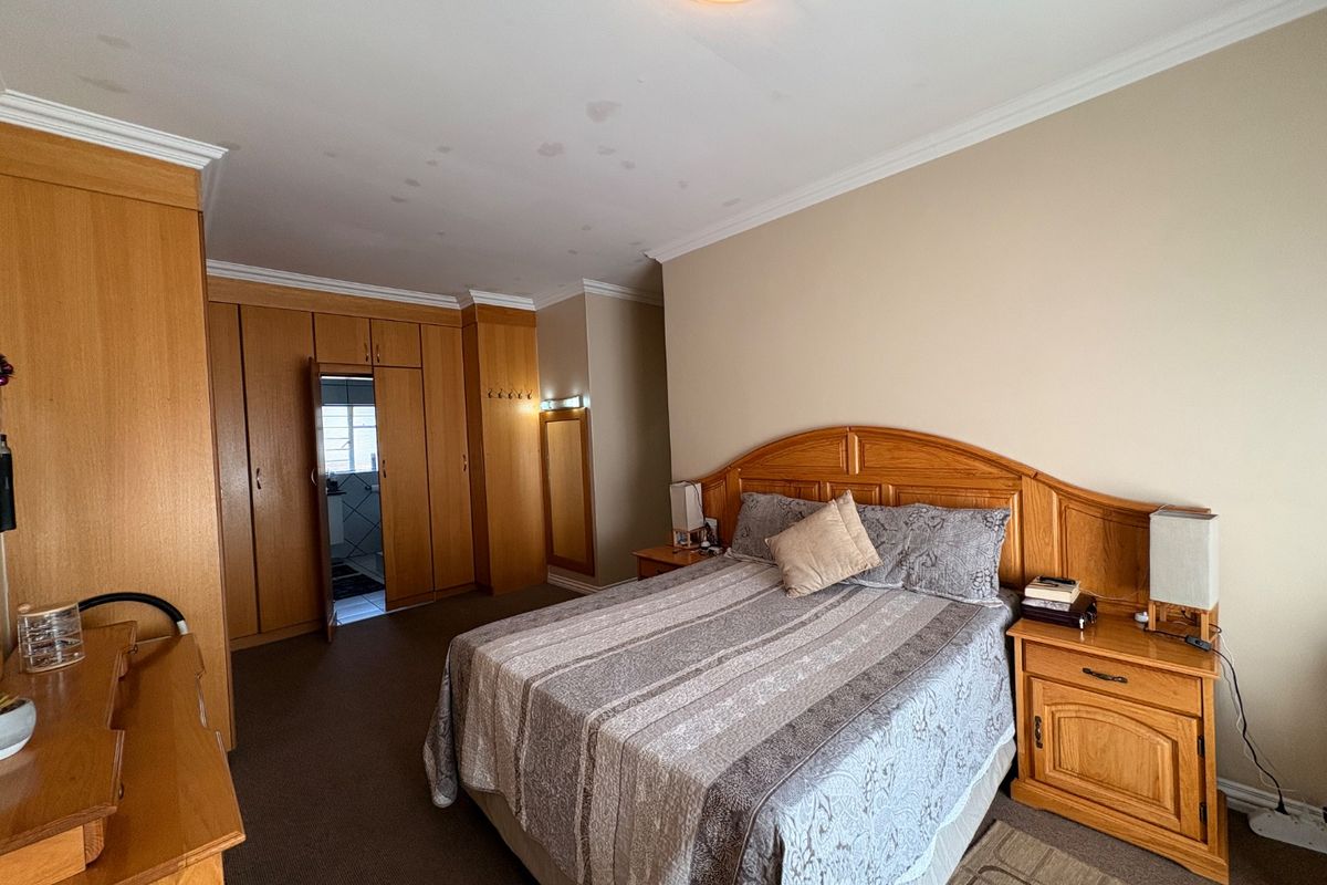Spacious bedroom featuring extensive built-in wooden cabinetry, integrated headboard, and direct access to an en-suite bathroom.