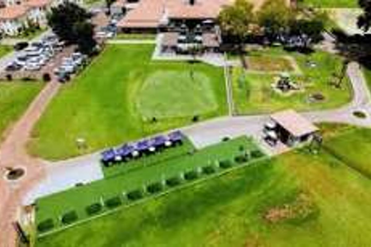 Aerial view of the property grounds featuring landscaped lawns, paved pathways, and access to golf course facilities.
