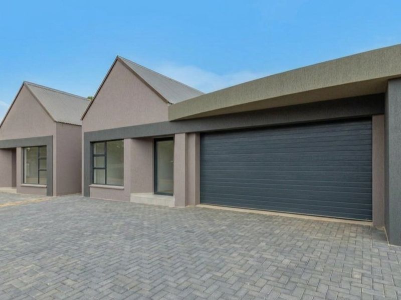 Modern exterior view of the property featuring a paved driveway, double garage with sectional door, and contemporary architectural facade.