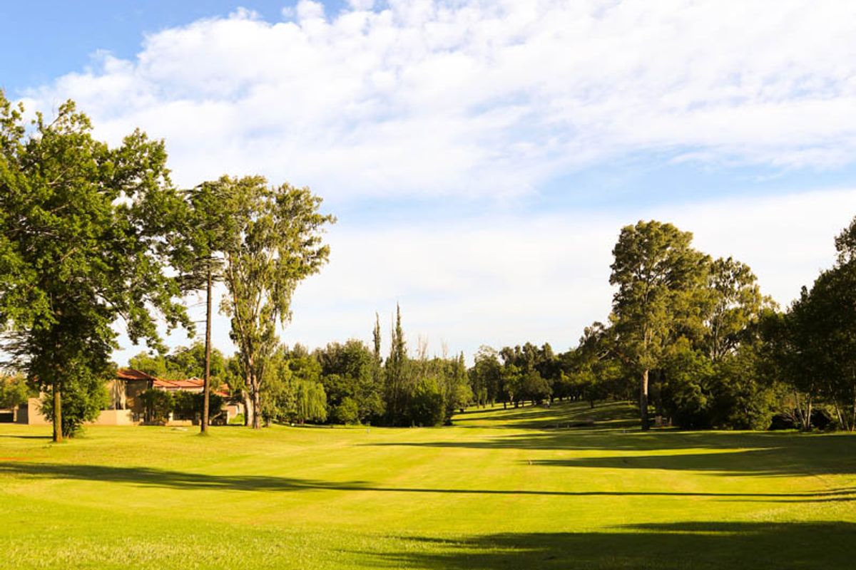 A scenic view of a well-maintained grassy landscape and mature trees, characteristic of a residential estate or golf course setting.