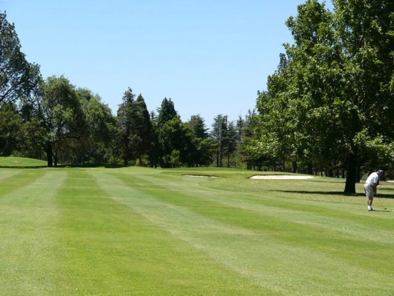 A view of a well-maintained golf course fairway with mature trees and sand bunkers, showcasing the scenic landscape of the residential estate.
