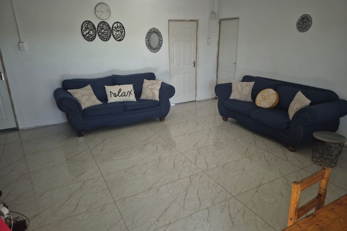 A spacious living room featuring large format marble-look floor tiles and neutral walls, providing a clean and open foundation for the living area.
