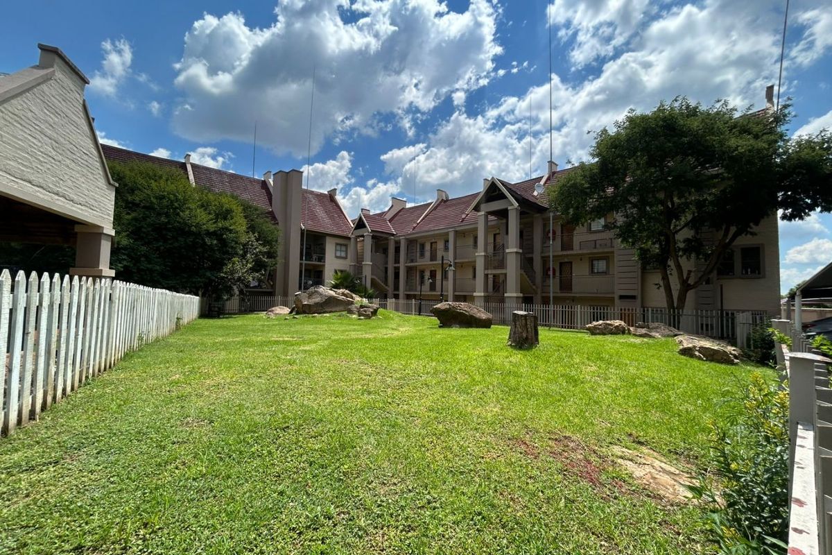 A view of the apartment complex exterior featuring a well-maintained communal lawn area with landscaping and surrounding residential building facades.