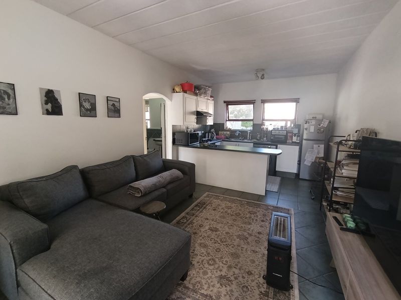 An open-plan living area featuring a kitchen with built-in cabinetry, a breakfast counter, and tiled flooring throughout the combined space.