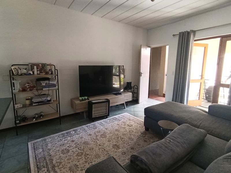 A comfortable living room featuring tiled flooring, a panelled ceiling, and direct access to an outdoor patio area.