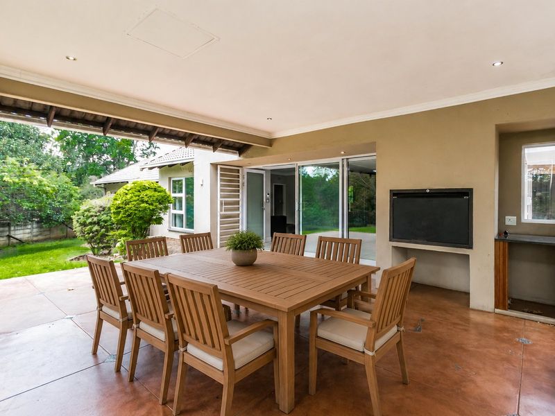 Covered patio area featuring a built-in braai, tiled flooring, and direct access to the garden through sliding glass doors.