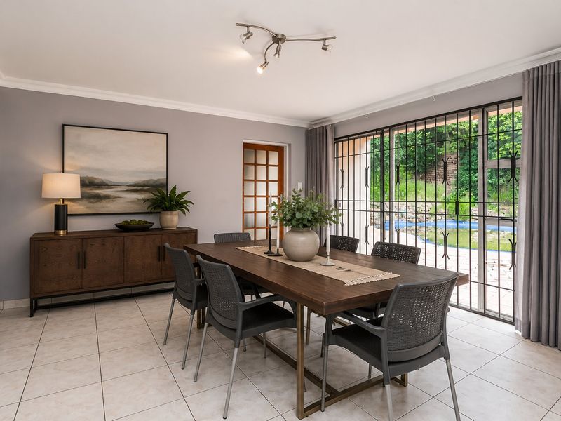 A bright dining room featuring tiled flooring, modern track lighting, and large sliding glass doors with security bars providing direct access to the pool area.