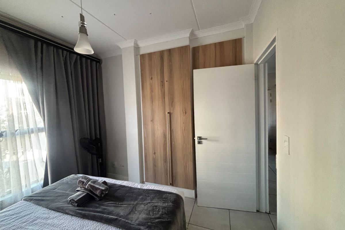 A well-maintained bedroom featuring built-in wooden cabinetry, tiled flooring, and a neutral color palette, offering a clean and functional living space.