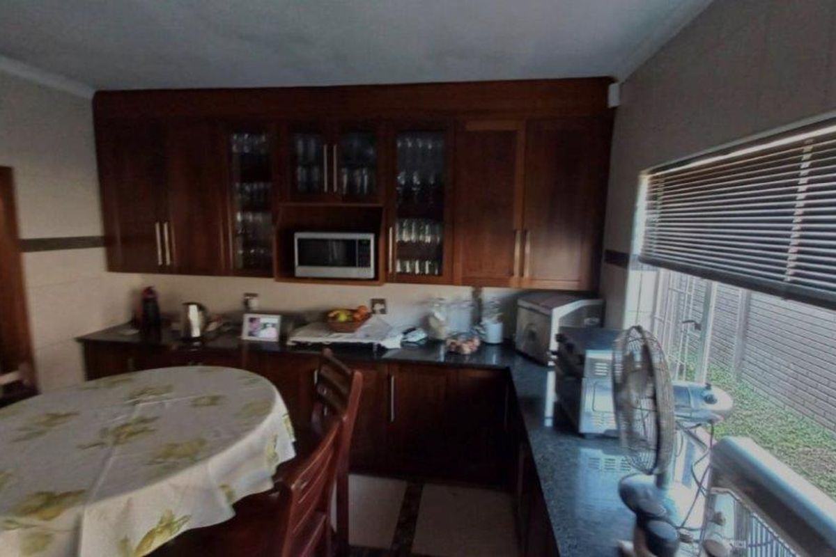 A functional kitchen featuring dark wood cabinetry, granite countertops, and a built-in microwave, offering a classic aesthetic with practical storage and workspace.