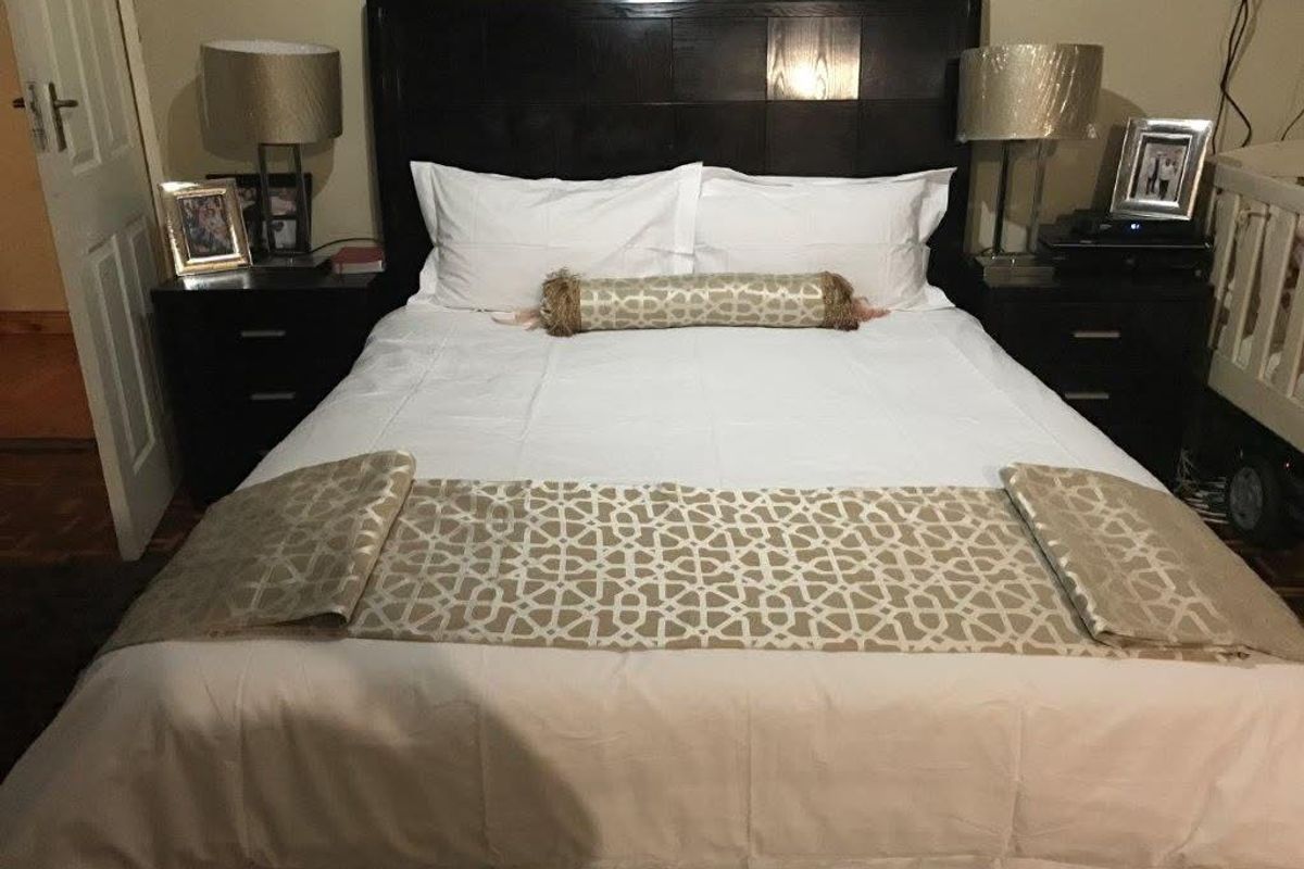 A well-maintained bedroom featuring a dark wood headboard and neutral wall finishes, providing a comfortable and functional sleeping space.