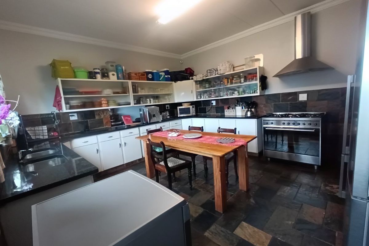 Spacious kitchen featuring dark stone countertops, slate flooring, stainless steel extractor fan, and a large gas range, offering ample storage and prep space.