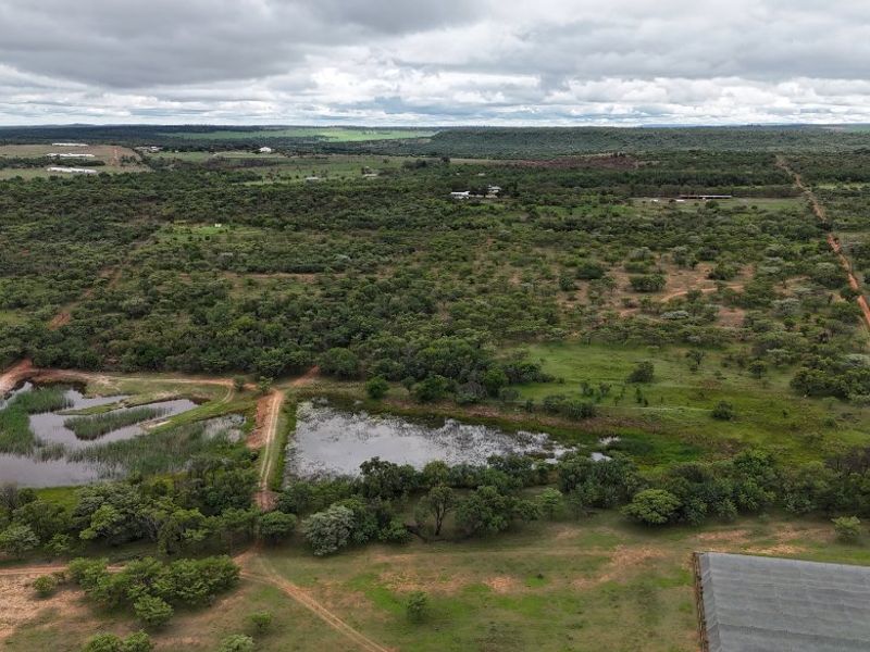 An expansive aerial view of the farm property, showcasing natural dams, indigenous vegetation, and dirt access roads across the landscape.