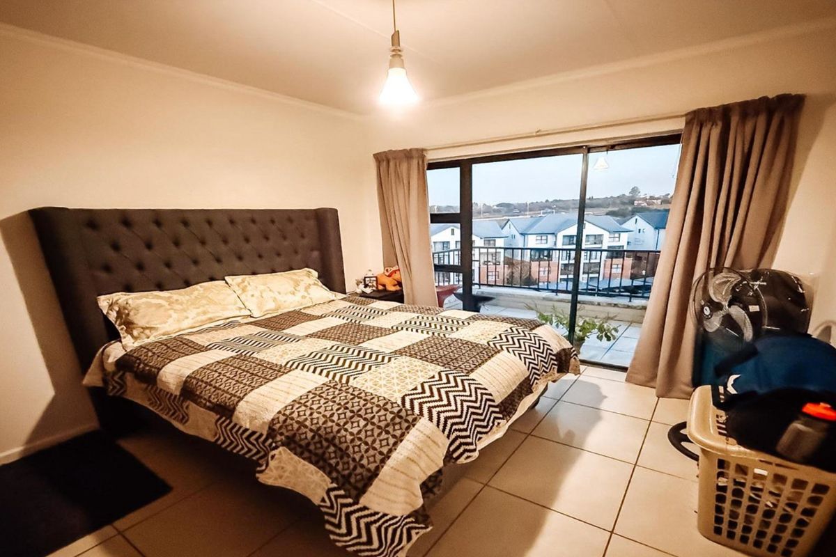 A bedroom featuring tiled flooring and large sliding glass doors that open onto a balcony with neighborhood views.