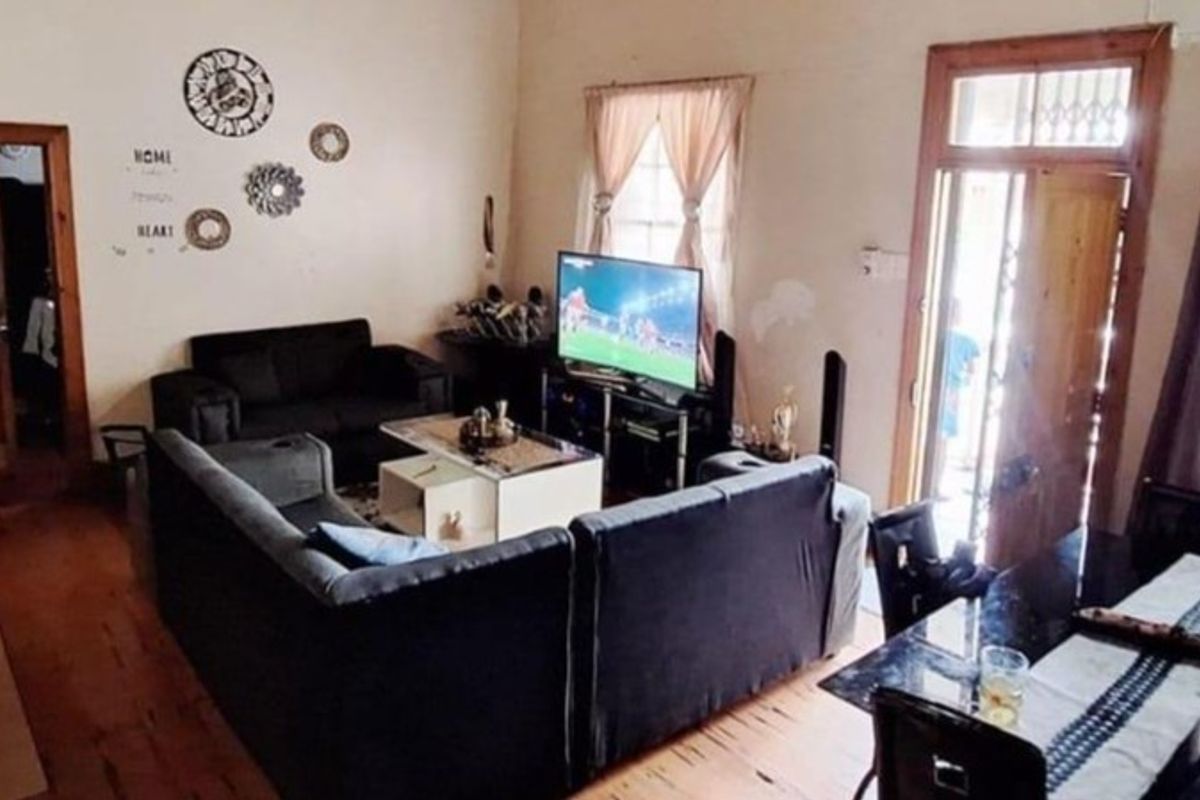 A living room featuring timber flooring, wooden door frames, and natural light through multiple windows.