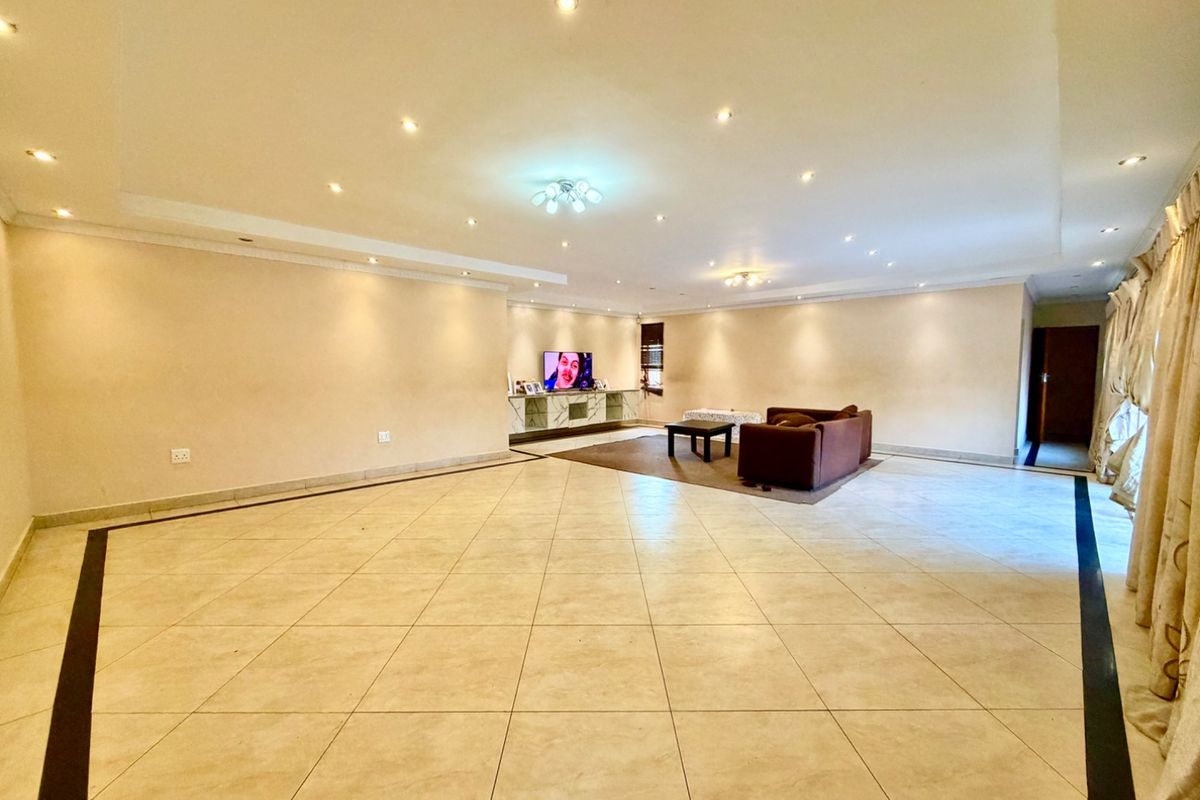 Spacious open-plan living area featuring large format floor tiles, recessed downlighting, and a built-in media console.