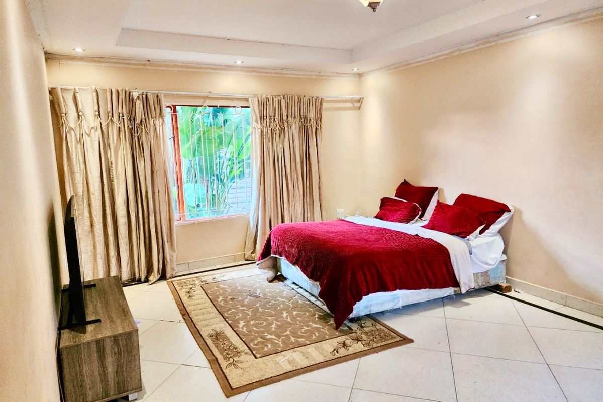 Spacious bedroom featuring tiled flooring, recessed ceiling lighting, and large windows with curtain tracks.